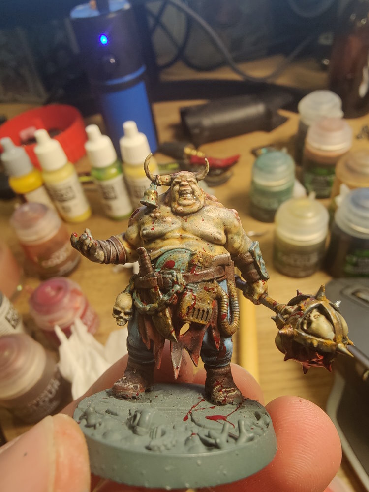 Filip holding a painted miniature beside hobby paints