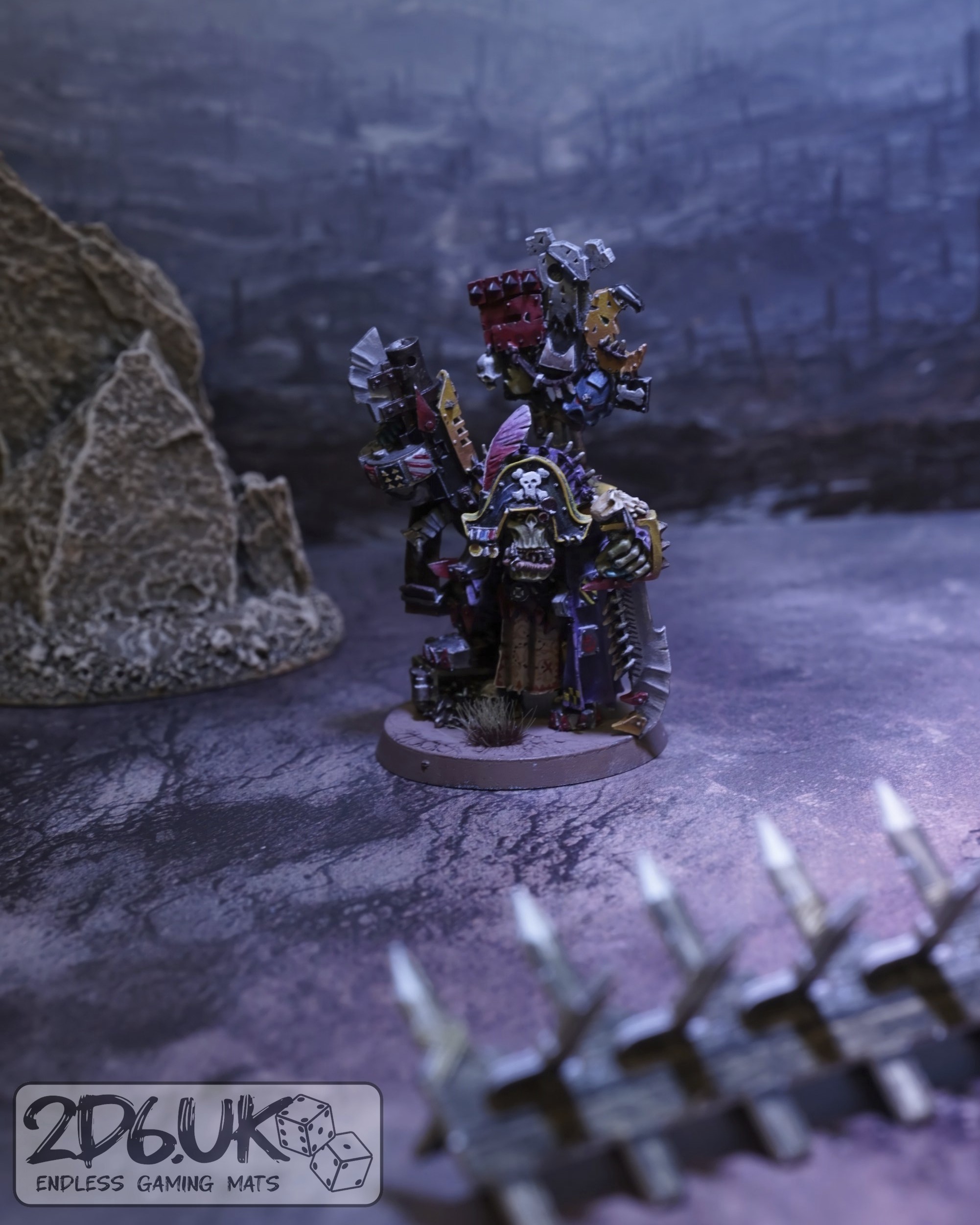 Painted ork character framed by foreground terrain and a softly blurred ruined-city backdrop